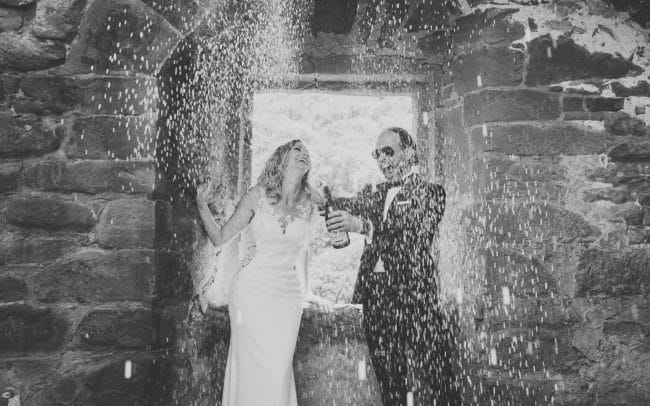 Hochzeitsfotografie Brautpaar öffnet Flasche Champagne Schwarz/Weiss